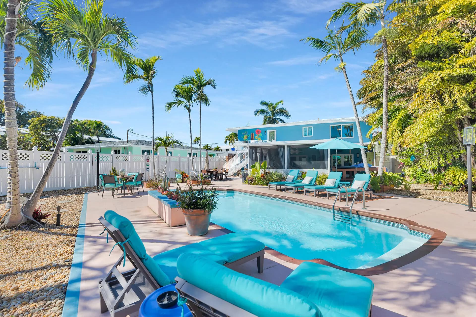 Private swimming pool and sun deck framed by palms, with the house behind