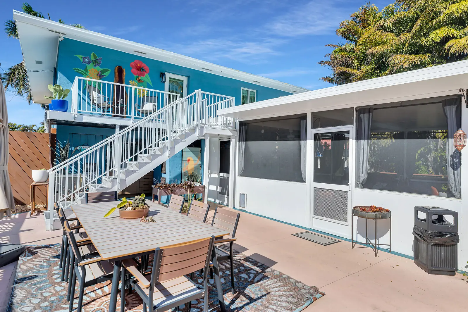 Patio dining area beneath the painted staircase and screened room