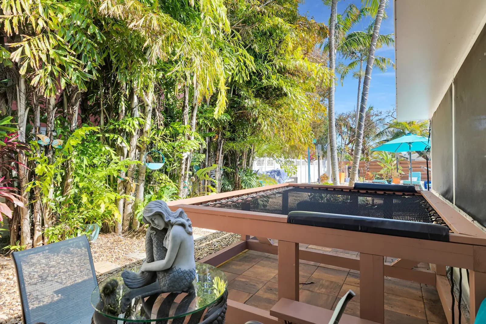 Tropical backyard with palms, art, and the pool beyond