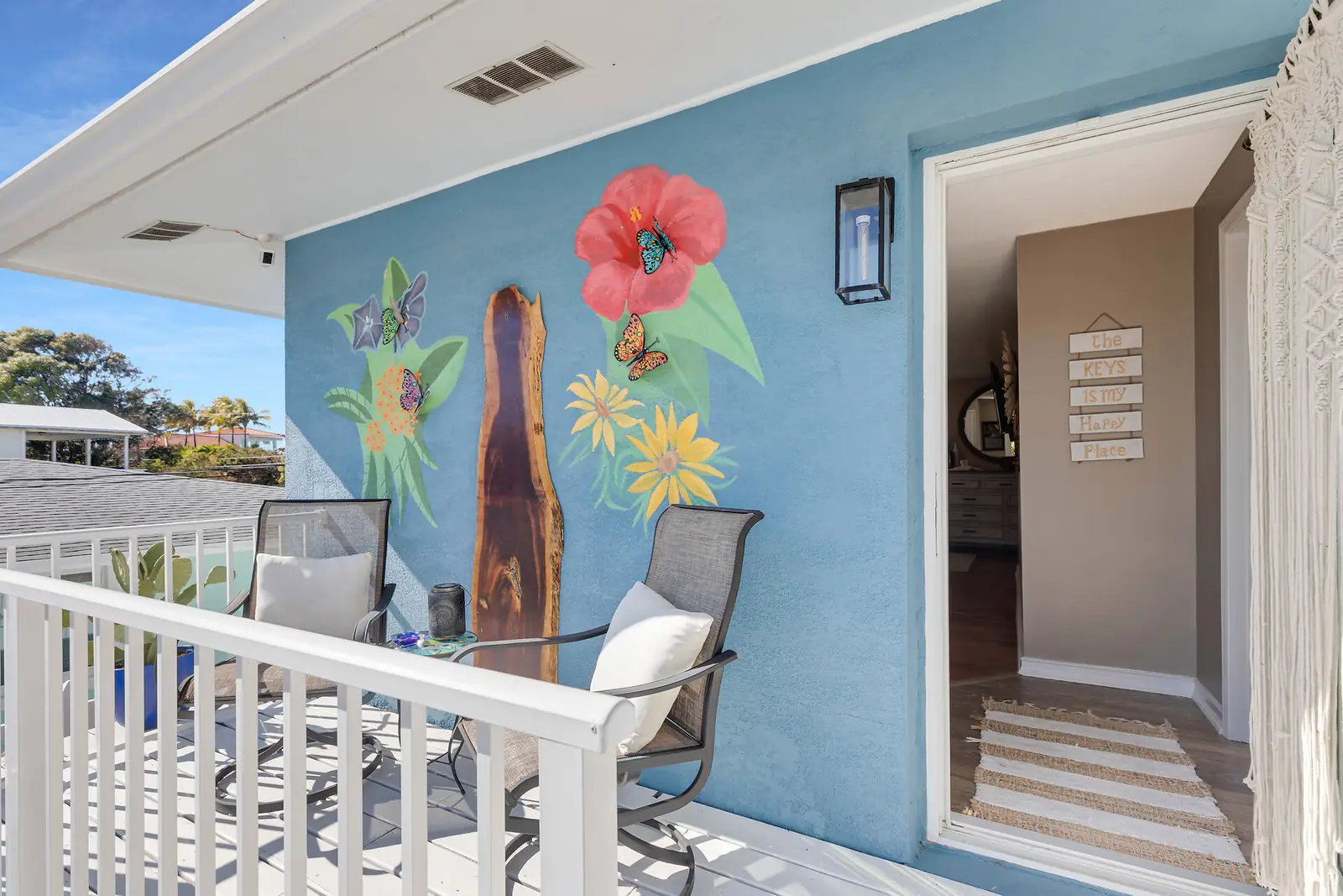 Private balcony with seating, mural, and Gulf views beyond
