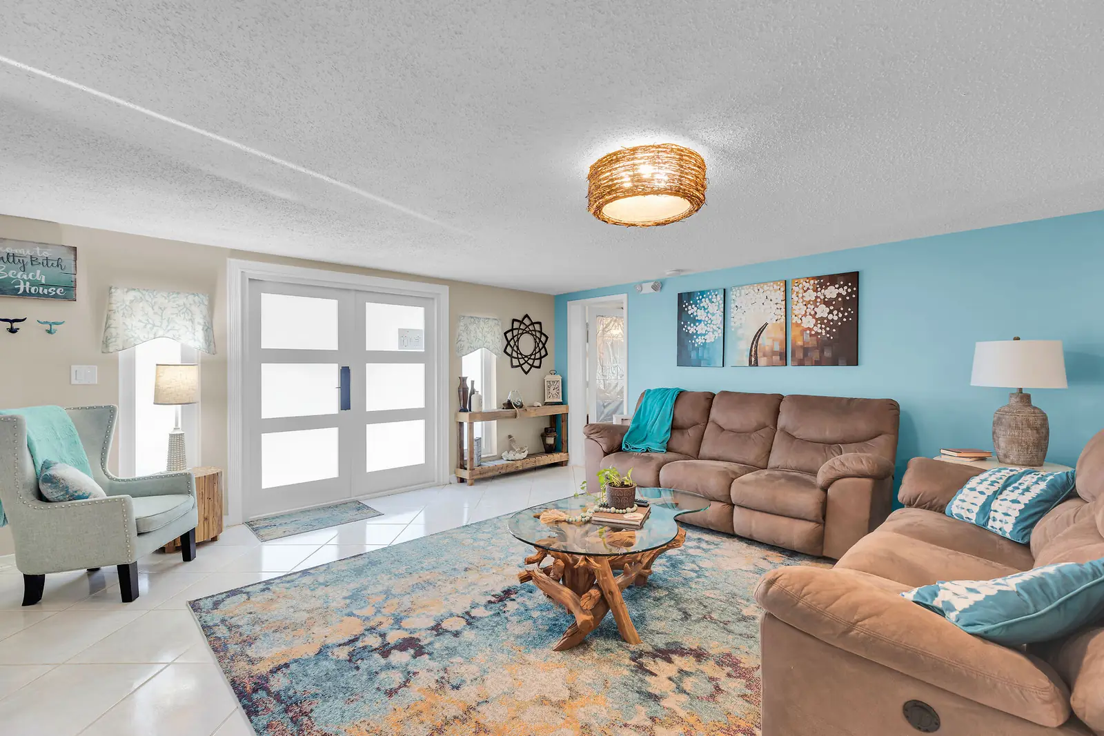Open living area with coastal accent wall and bright entry doors